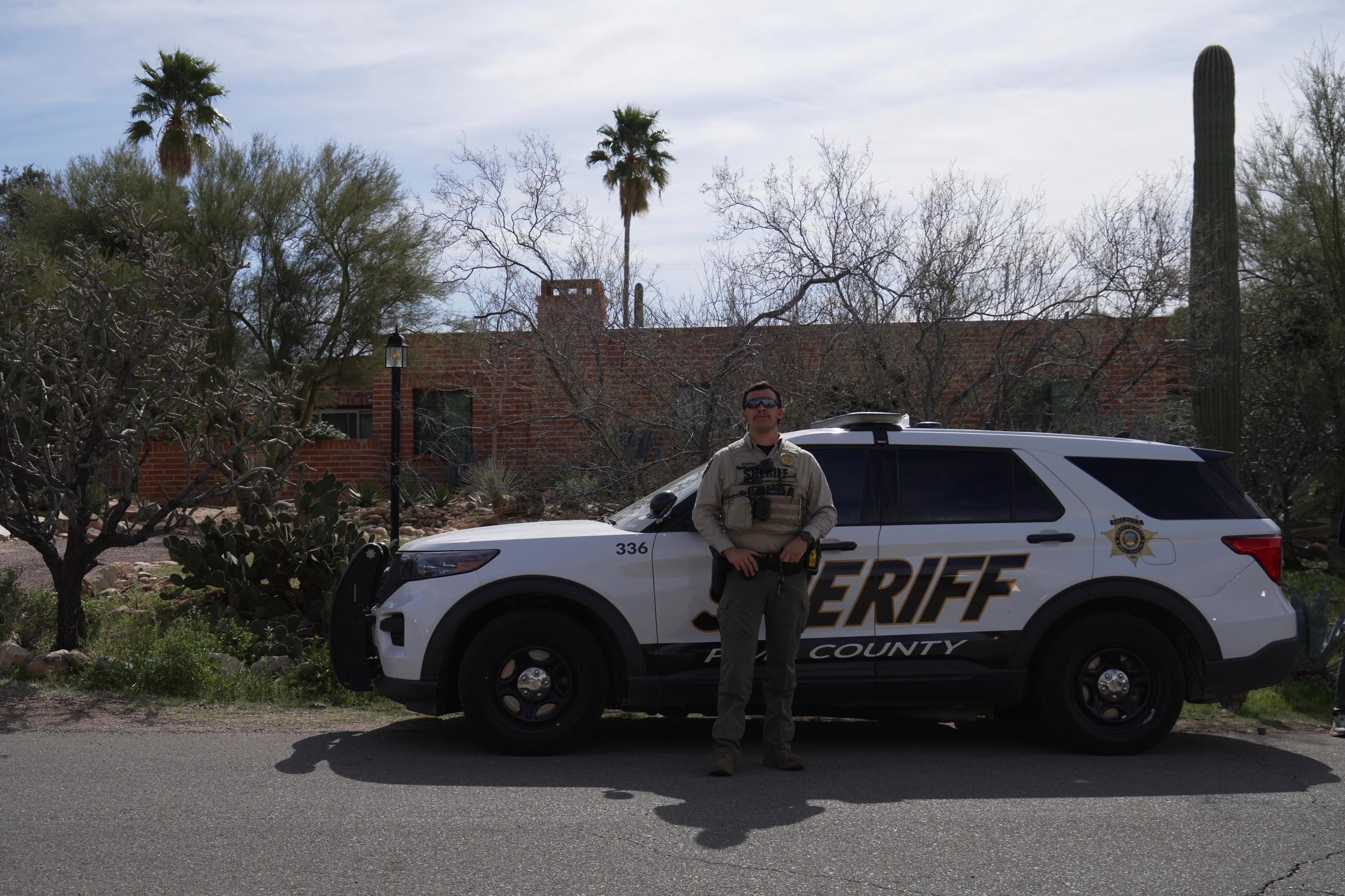 A Pima County Sheriff's Office member stands next to his vehicle in front of Nancy Guthrie's home.