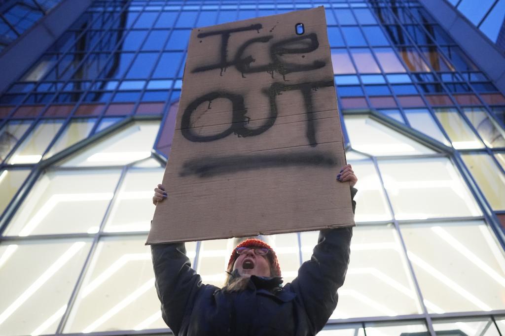 A demonstrator holds a sign reading "ICE OUT"