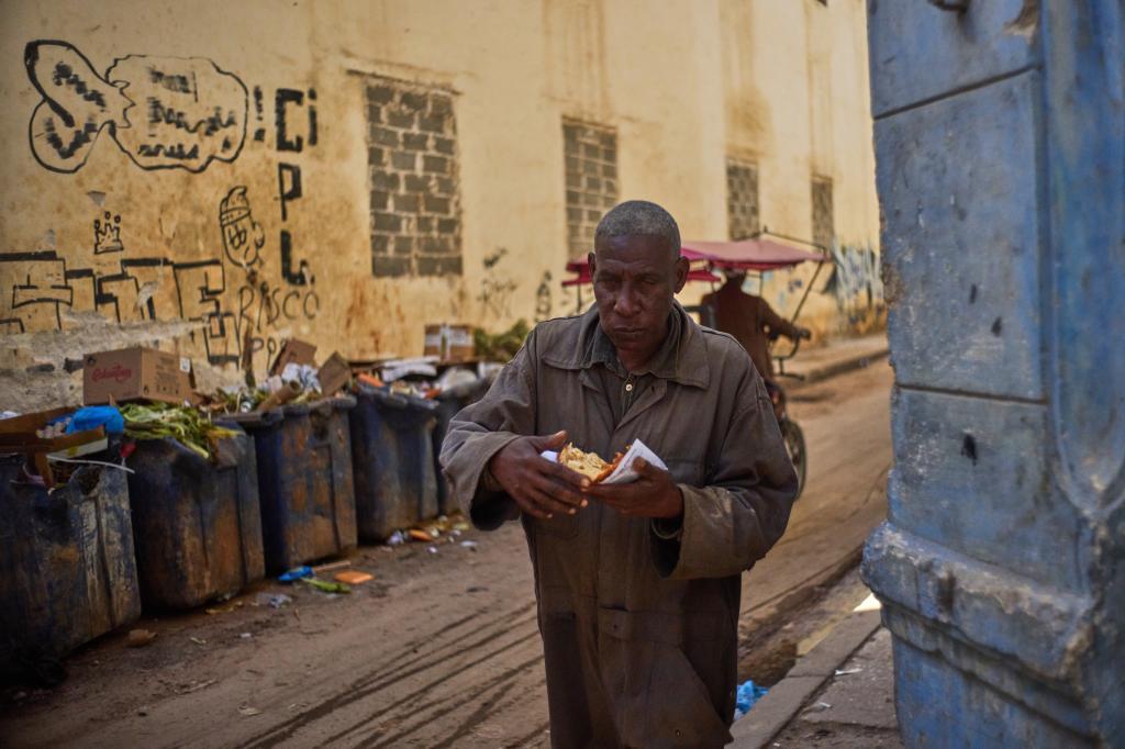 A pedestrian eats a slice of pizza in Havana.