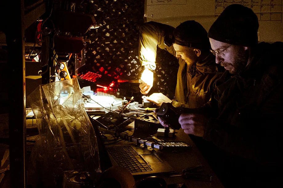 Roman and Max modify a drone in the basement of the Typhoon unit.