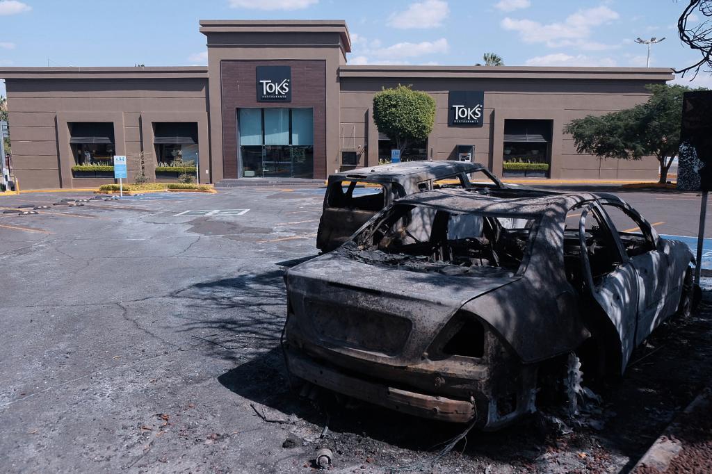 Charred vehicles sit in a parking lot sit outside a shopping mall in Guadalajara