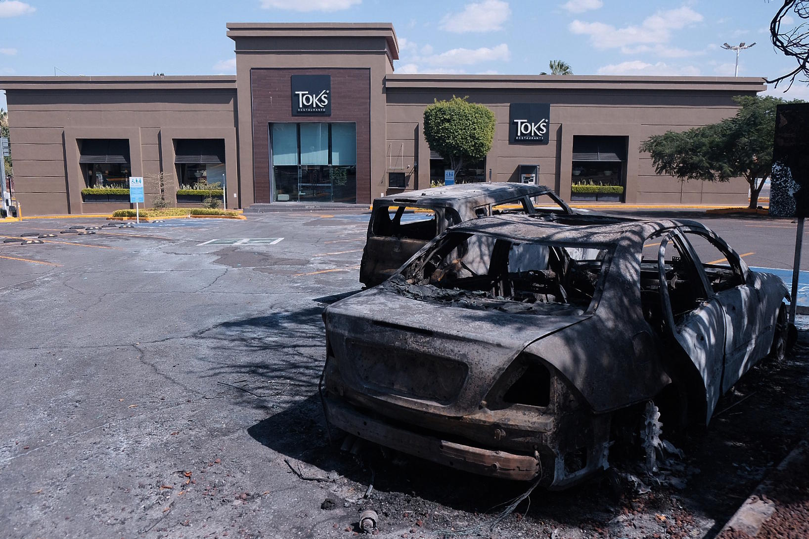 Burned-out vehicles lie in a parking lot in front of a shopping center in Guadalajara, Jalisco state.