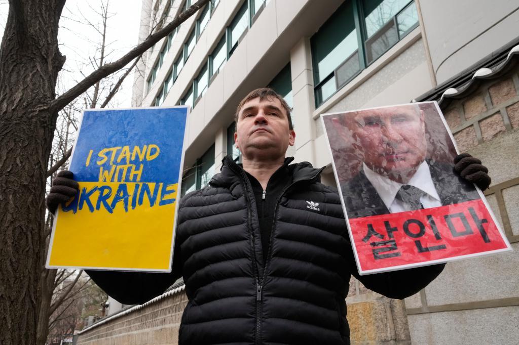 A Russian protester holds banners to denounce Russia's invasion of Ukraine on the fourth anniversary of the Russia-Ukraine war