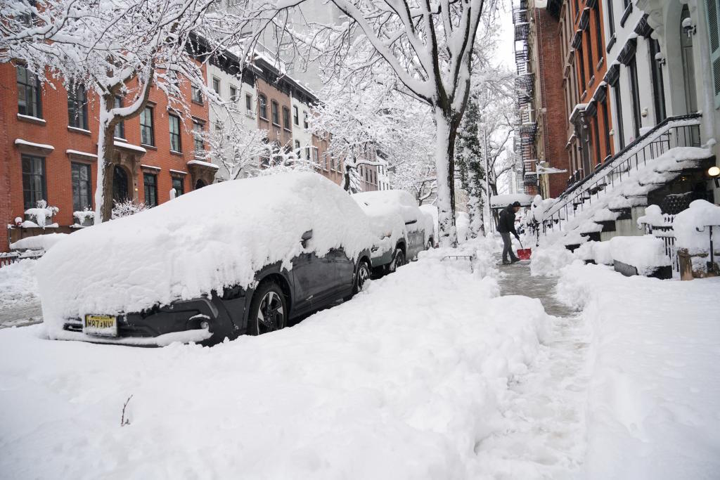 A man shovels snow off the sidewalk on East 19th Street in NY.