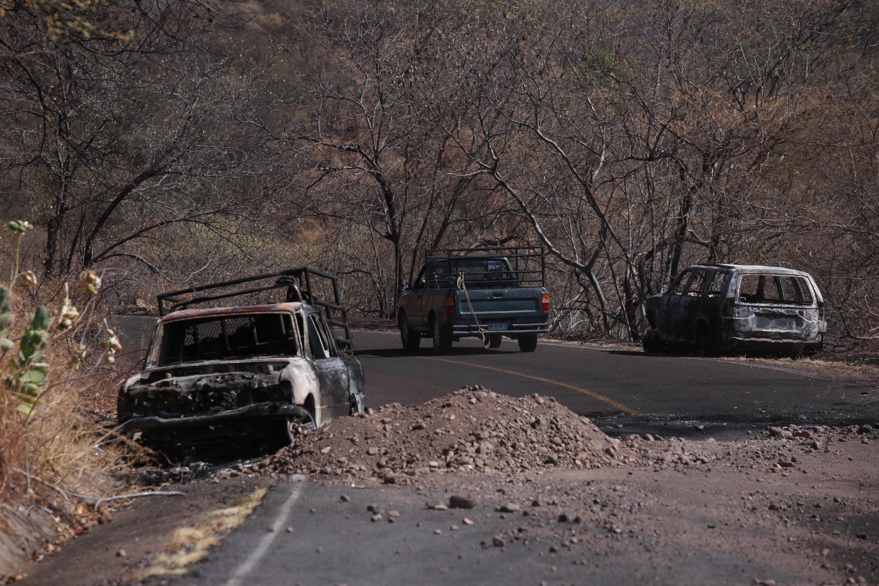 Charred vehicles sit on the side of a highway in Aguililla, Mexico.