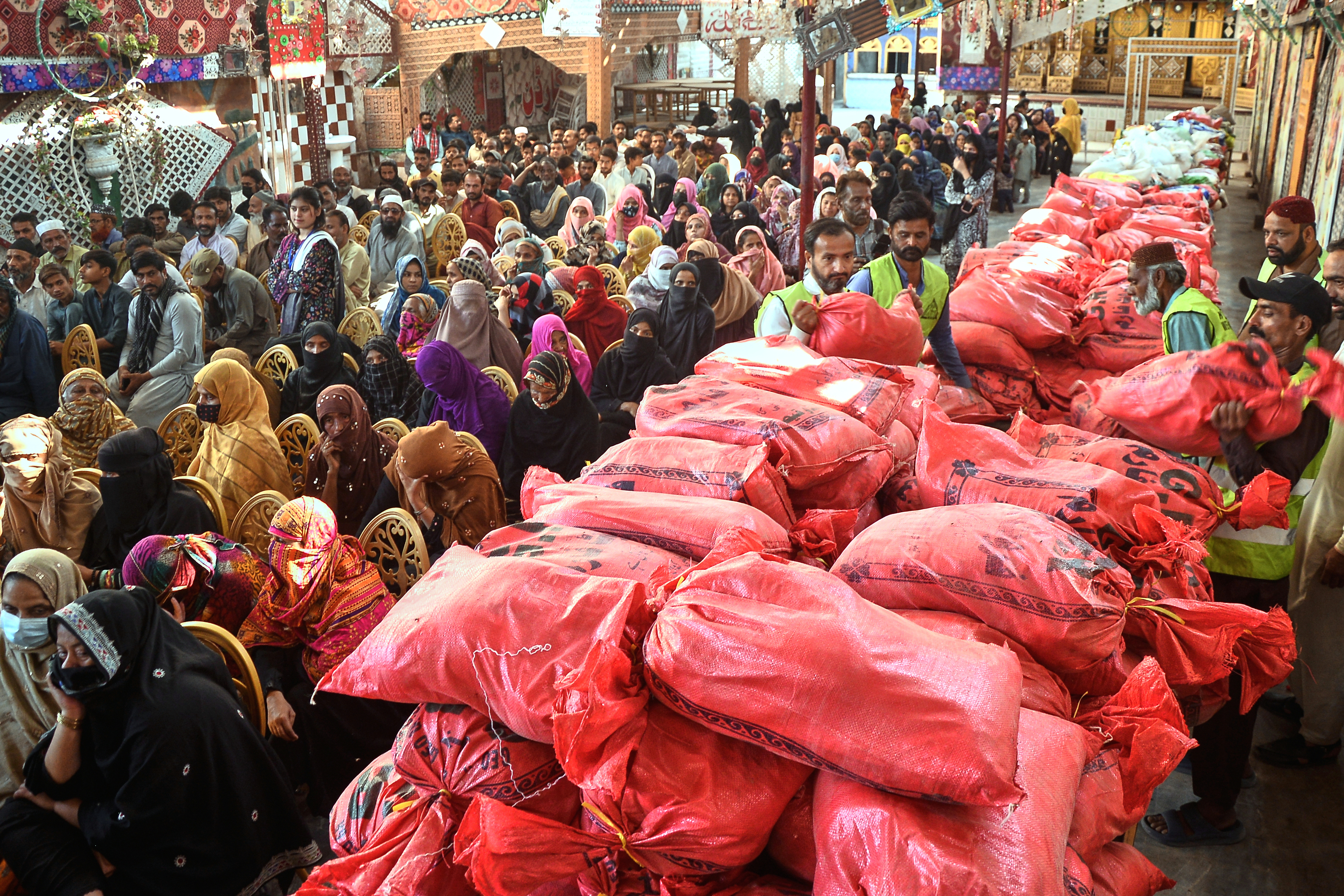 People wait for their turn to get free sack of relief aid distributed by a charity group for the Muslim's holy fasting month of Ramadan.