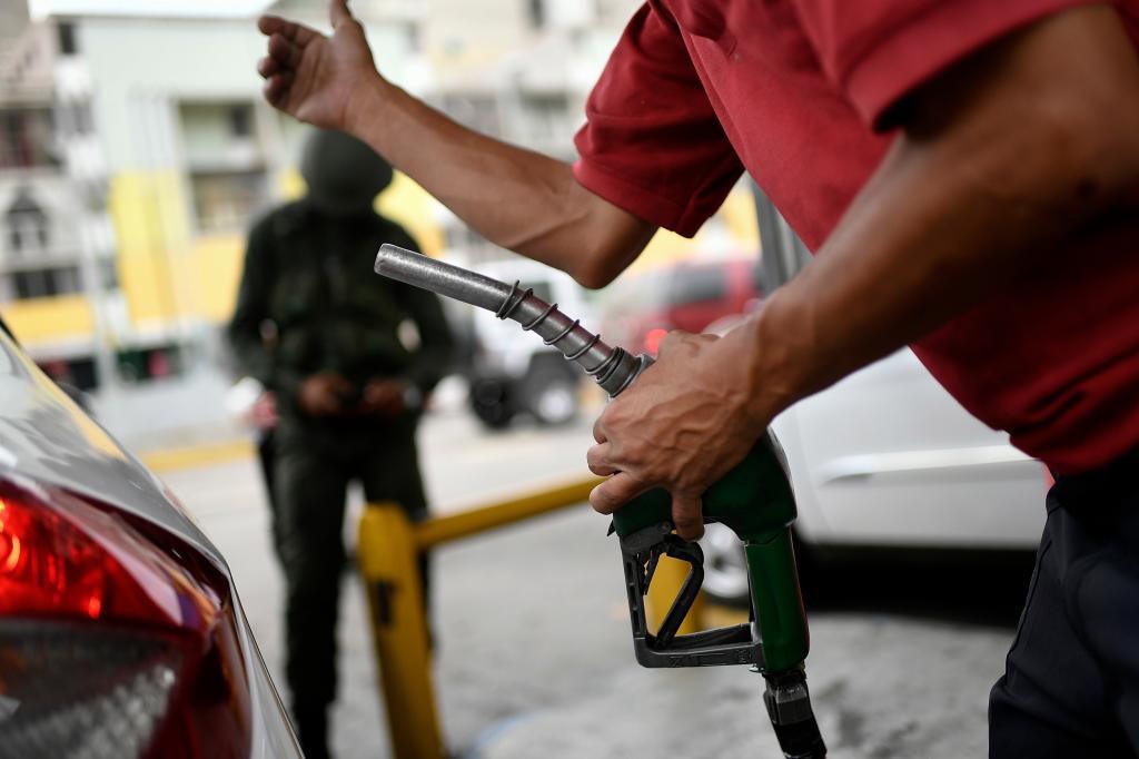 A worker holds a gas pump at a PDVSA state oil company gas station in Caracas.