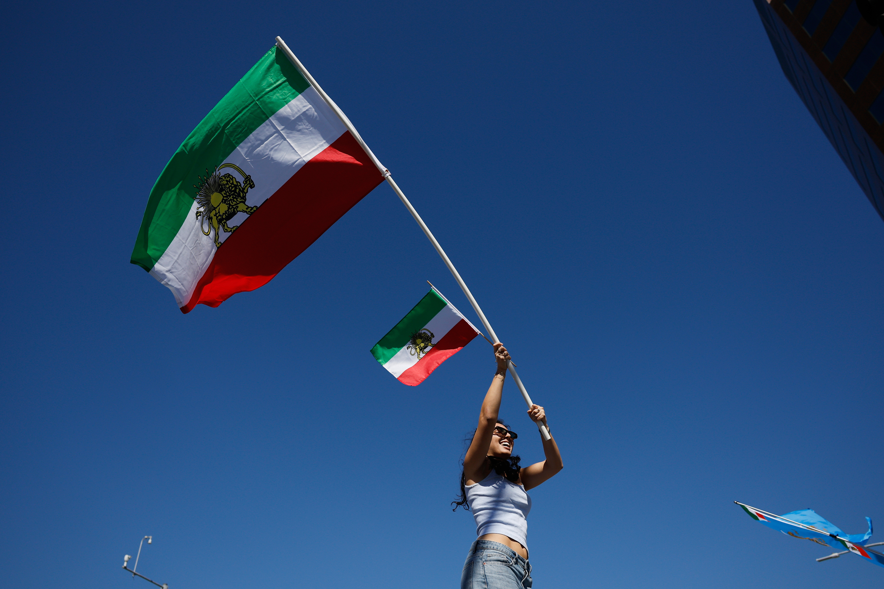 A demonstrator waves Iranian flags in reaction to the U.S. and Israeli strikes on Iran.