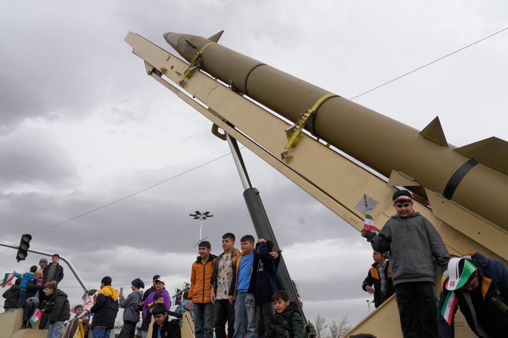 Boys stand on a launcher of an Iranian domestically-built missile during an annual rally marking 1979 Islamic Revolution