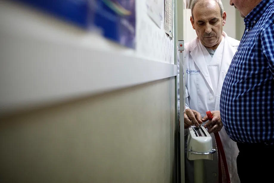 A doctor measures weight and waist circumference of a patient.