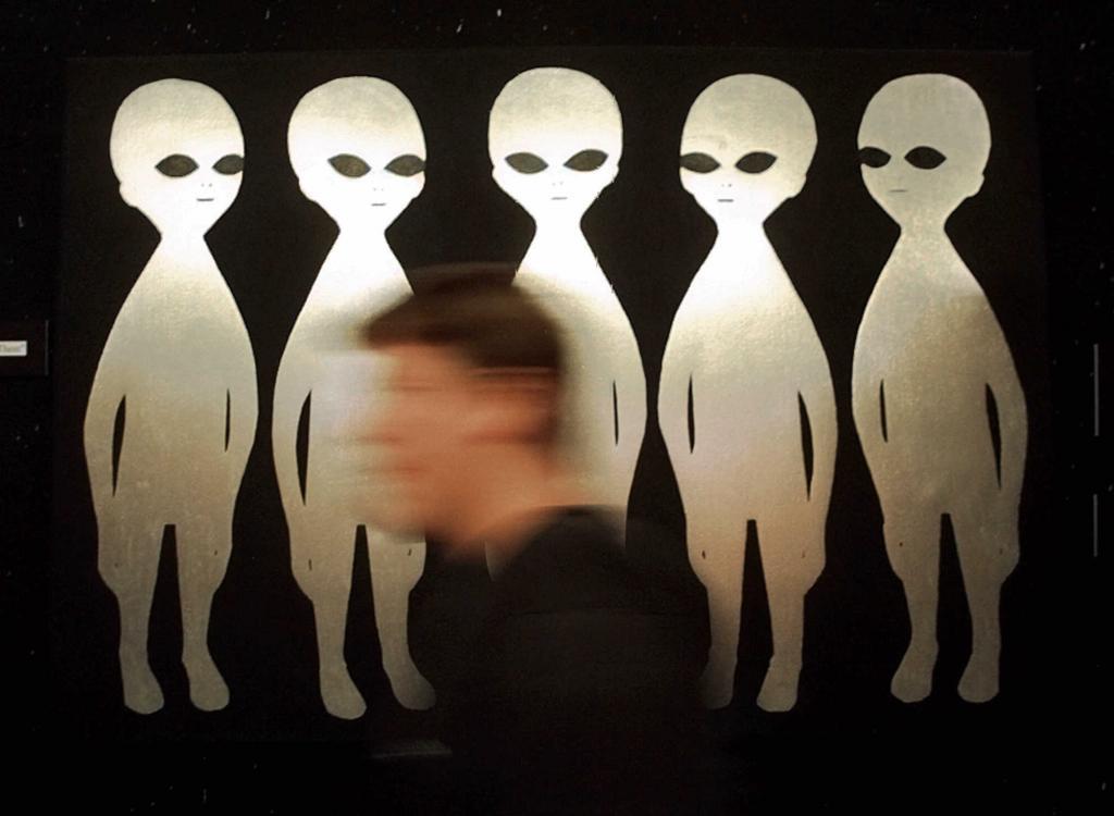 A visitor looking at a drawing of extraterrestrials at the Roswell International UFO Museum.