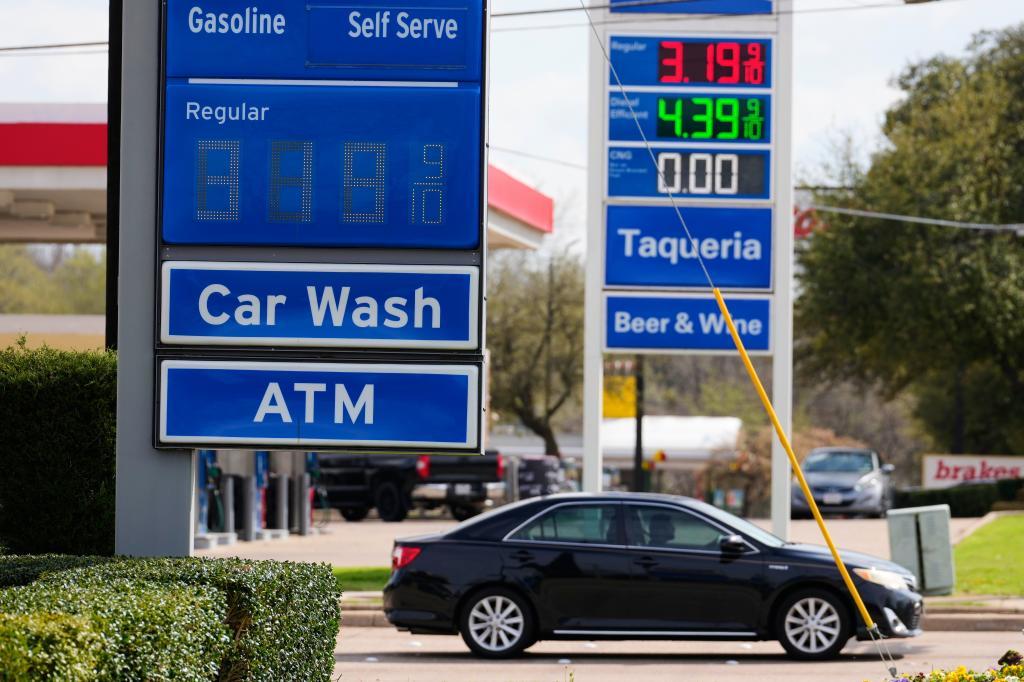 Gasoline prices are reflected on signs as motorist wait at a traffic light in Garland