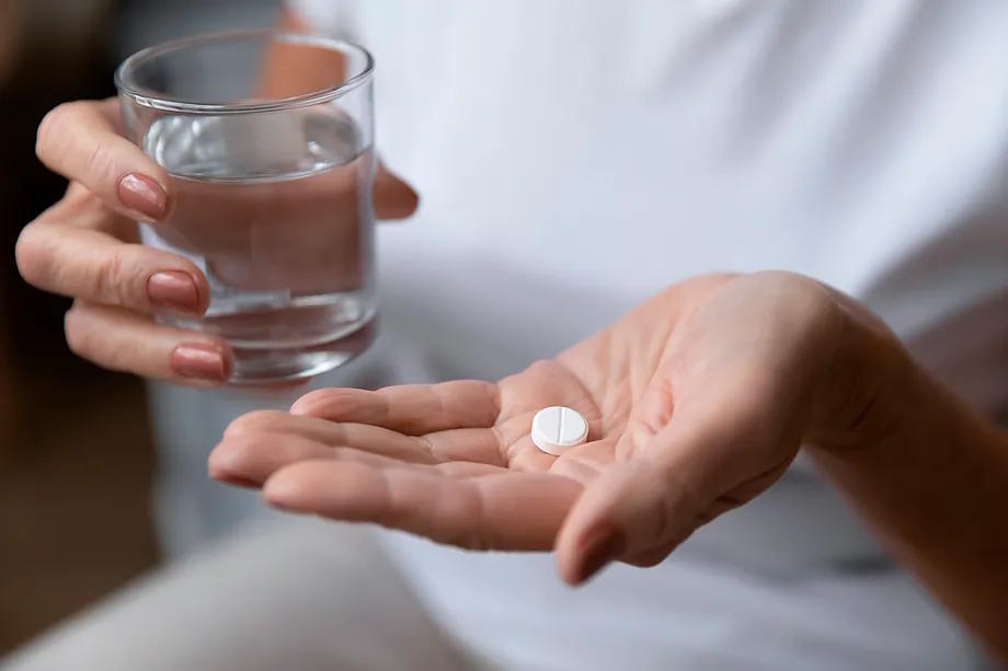 A woman takes an antibiotic with a glass of water