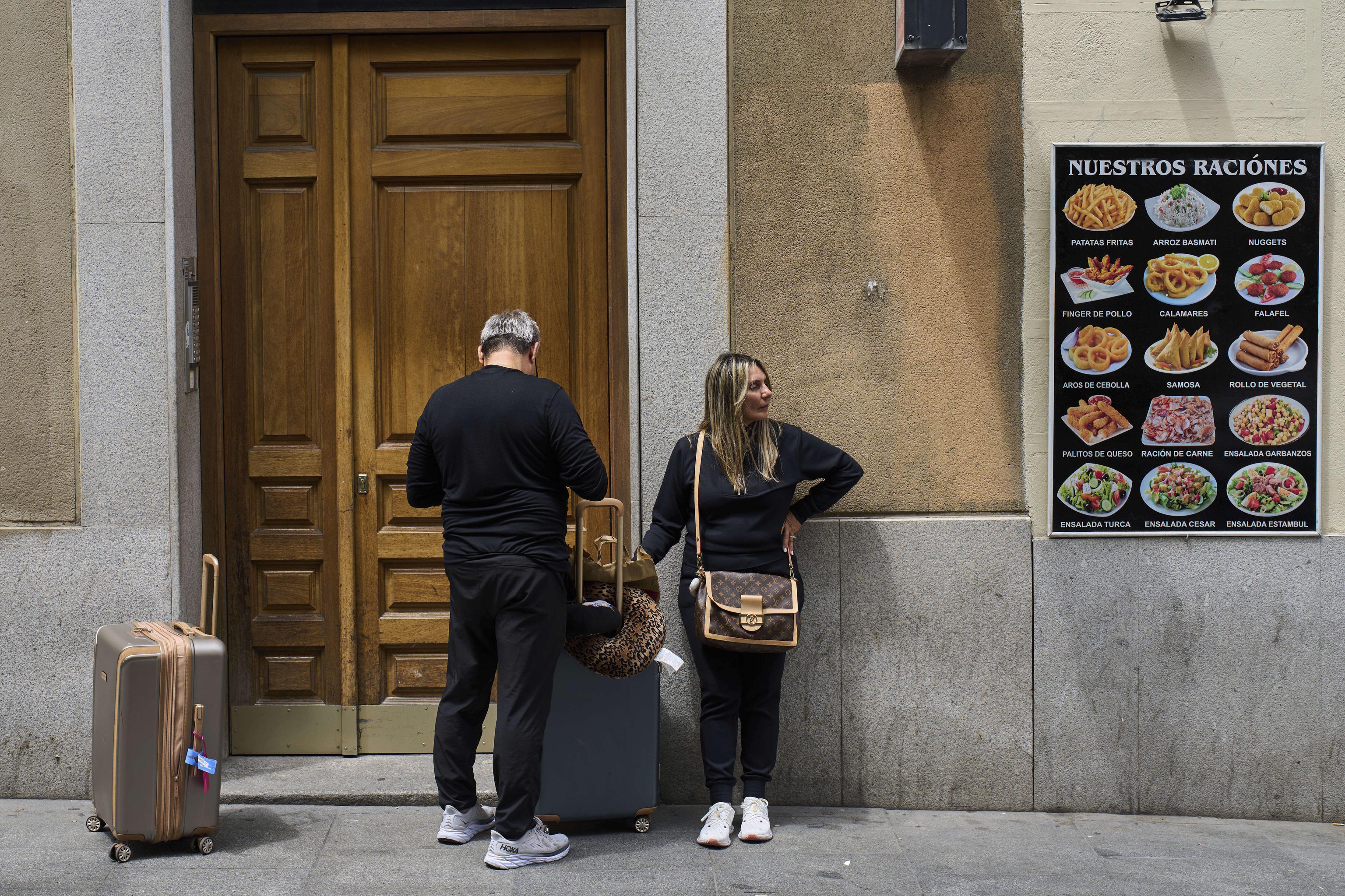 Tourists wait at the entrance of a building in downtown Madrid, Spain.