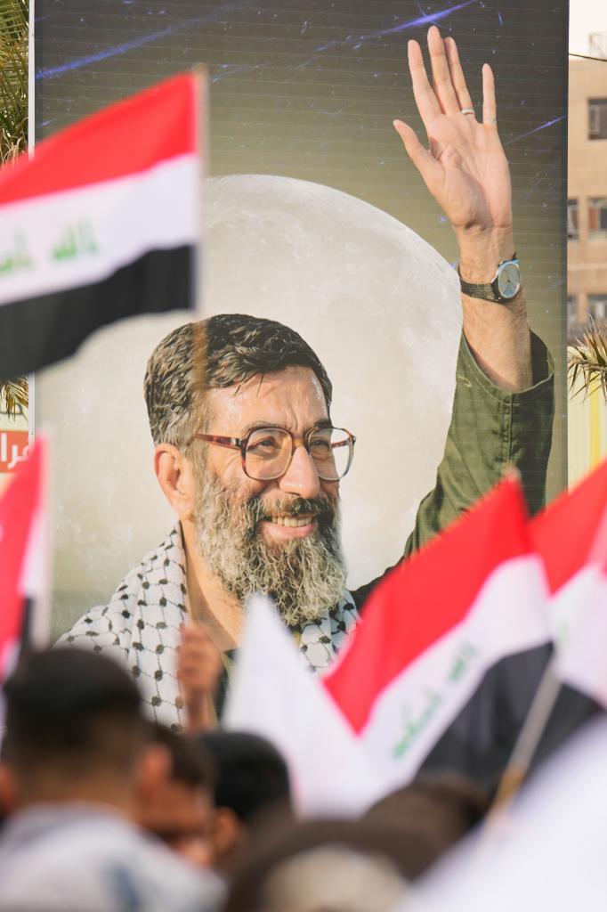 Protestors wave Iraqi national flags as another holds up an image of Supreme Leader Ayatollah Ali Khamenei,