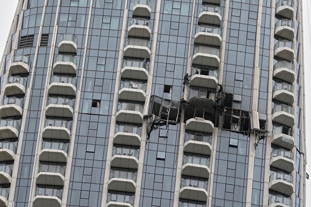 Workers inspect damage caused by a drone strike overnight at the Address Creek Harbour hotel in Dubai