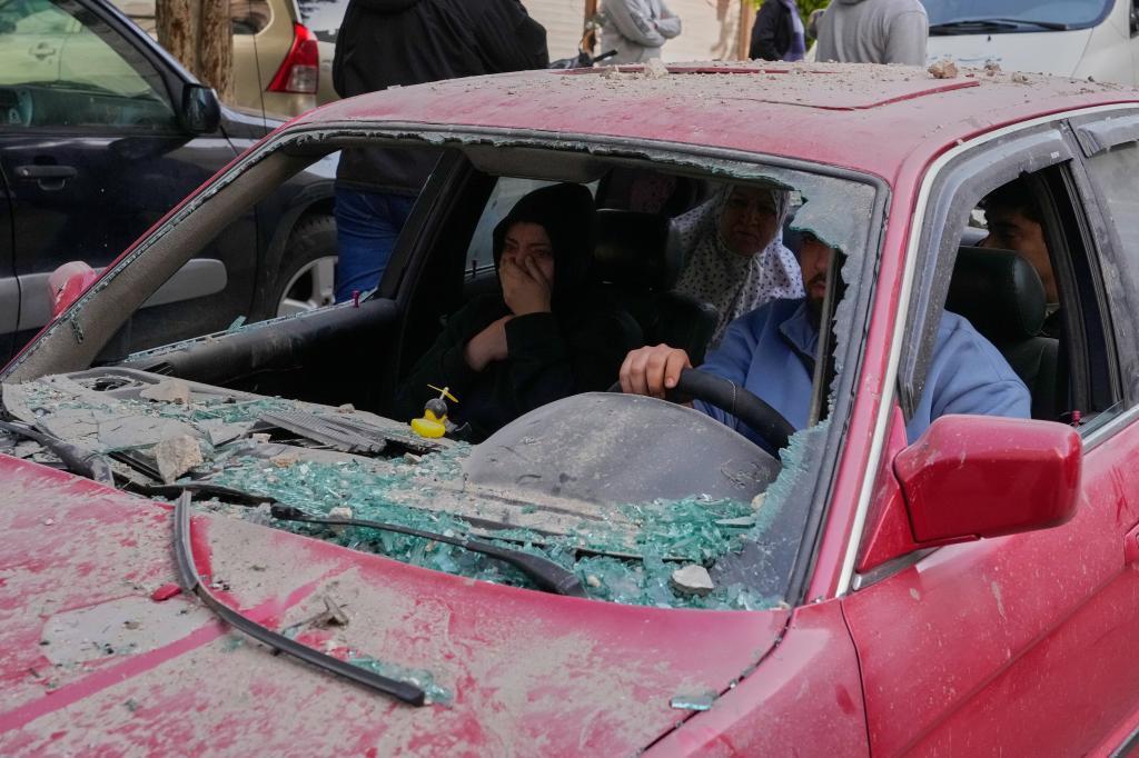 Family members ride in a damaged car, as they flee the site of an Israeli airstrike