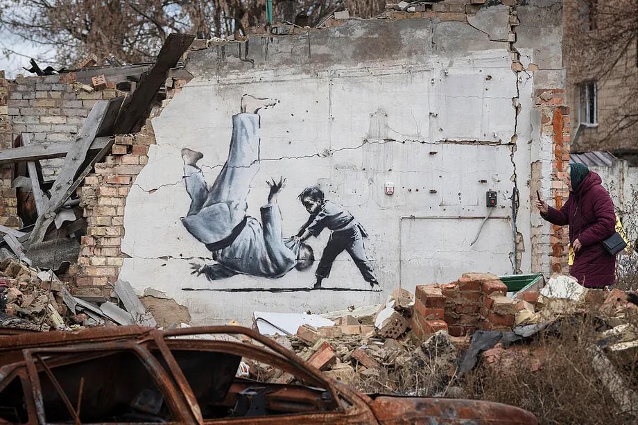 A woman photographs one of Banksy's works that appeared on destroyed buildings in Ukraine in the fall of 2022.