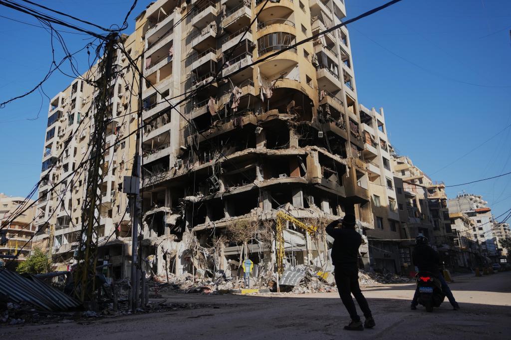 A man photographs a building damaged by an Israeli airstrike in Dahiyeh, Beirut's southern suburbs