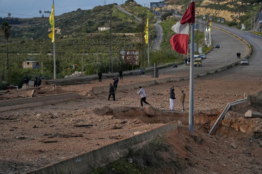 People inspect a crater following an Israeli airstrike that hit the Qasmiyeh Bridge near the coastal city of Tyre