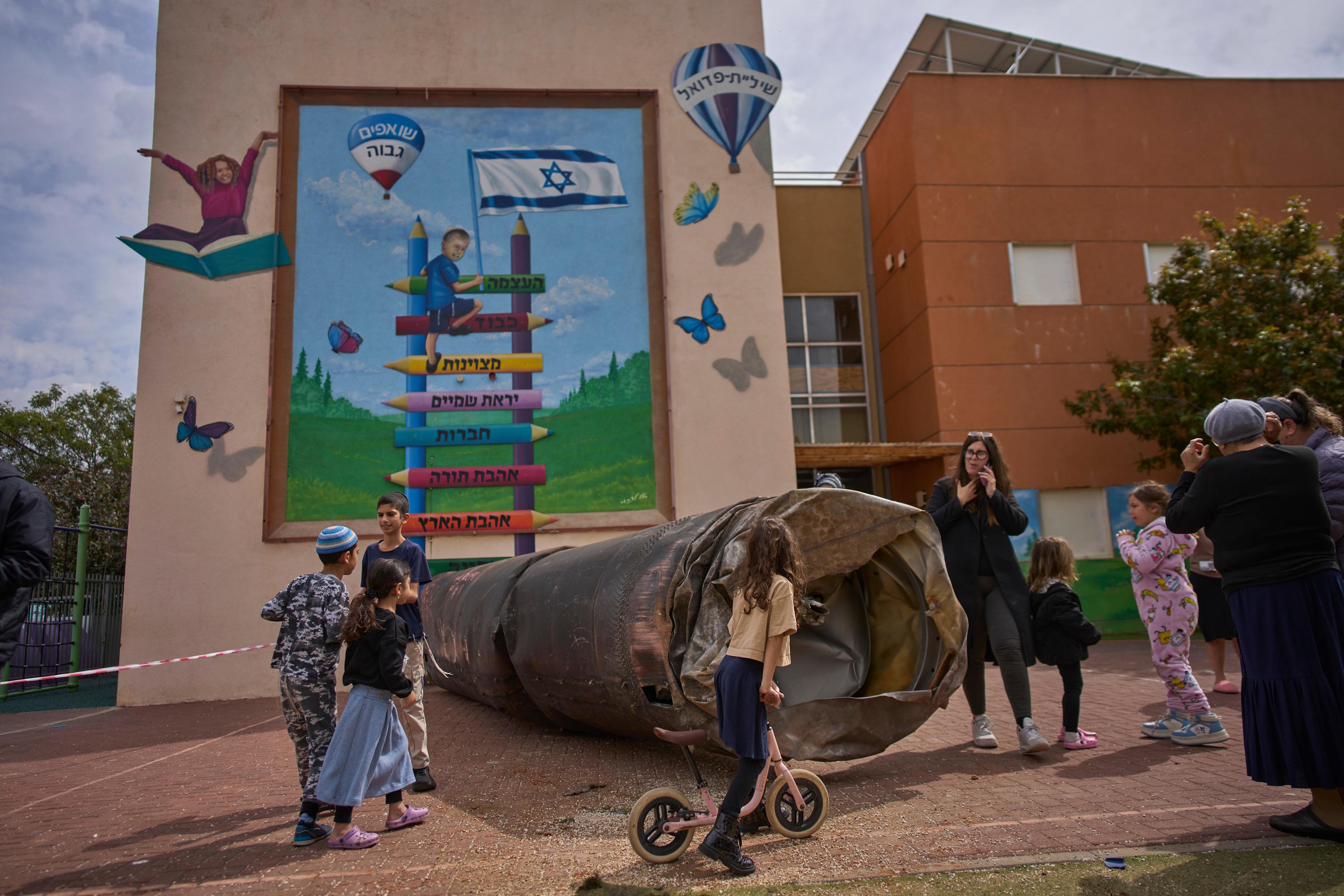Children play beside a fragment of an Iranian ballistic missile.
