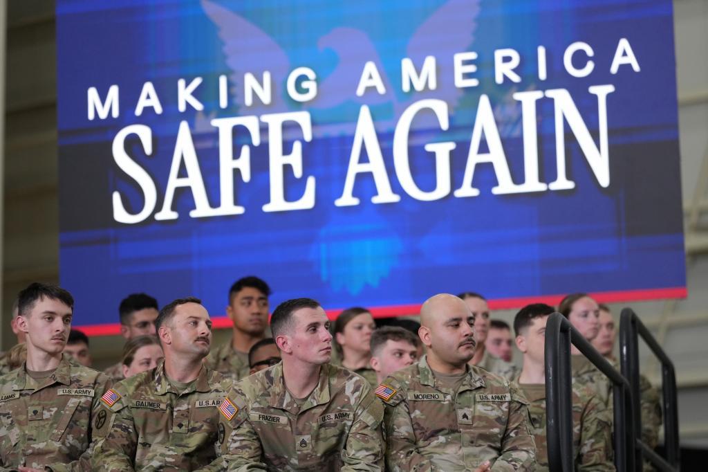 U.S. Army Soldiers on stage, look on as President Donald Trump