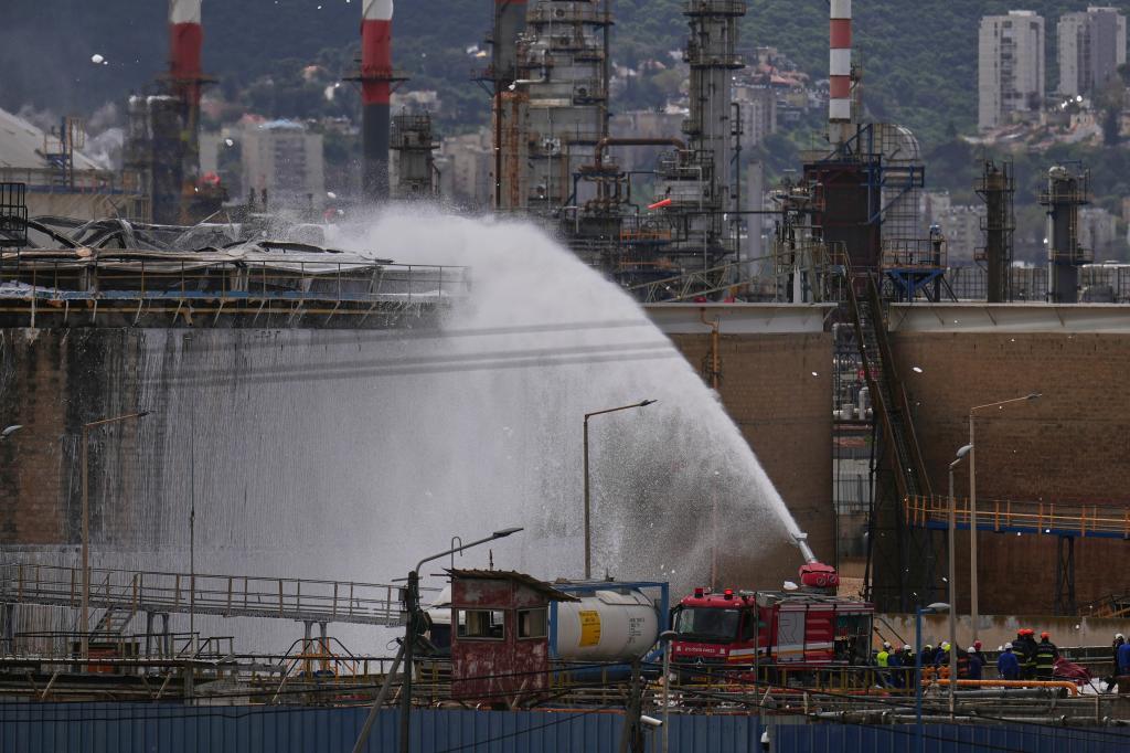 Firefighters work to extinguish a fire at the site of an Iranian missile strike in Haifa