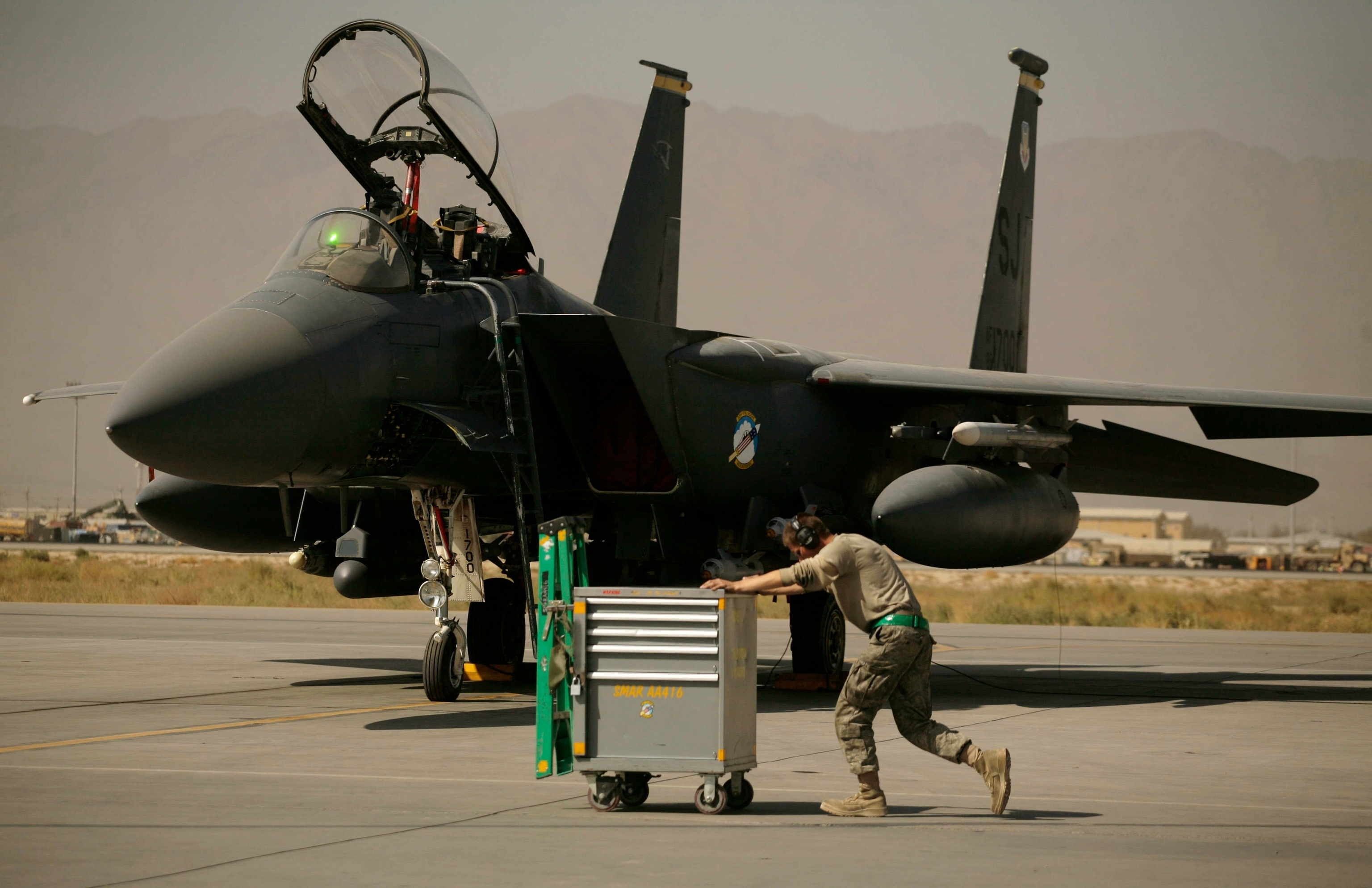 A U.S. Air Force airman pushes a cart past an F-15E Strike Eagle.