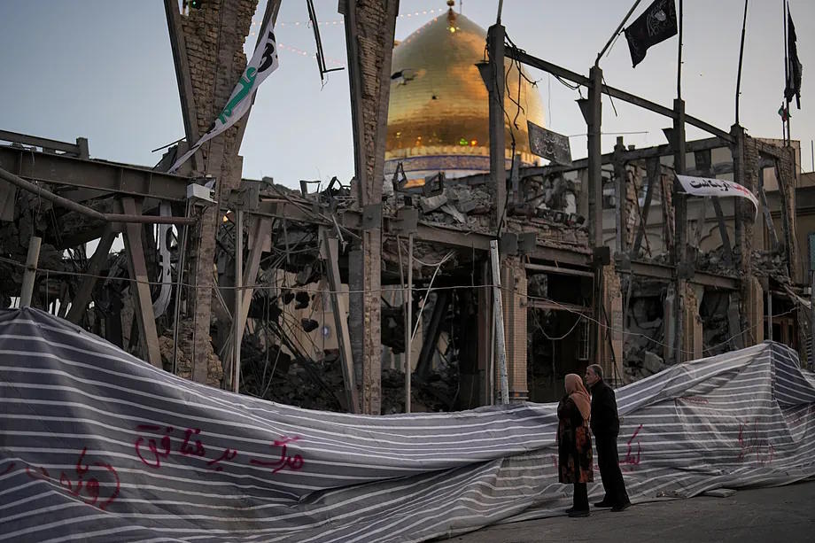 A destroyed building with a visible mosque in the background, which according to authorities was hit by US and Israel attacks in Zanjan, Iran.
