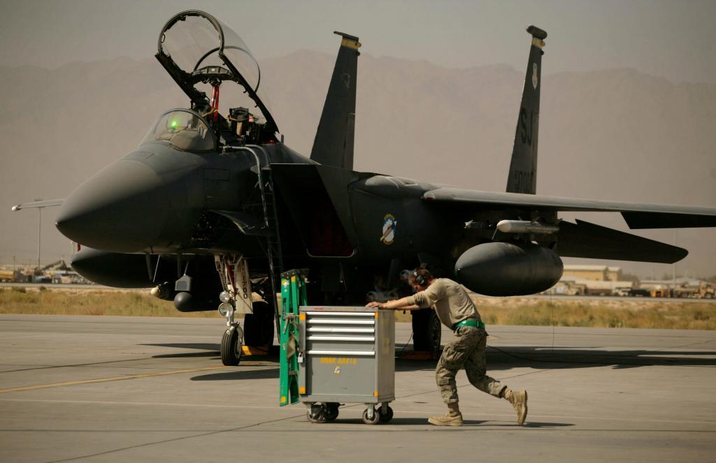A U.S. Air Force airman pushes a cart past an F-15E Strike Eagle at Bagram Air Field