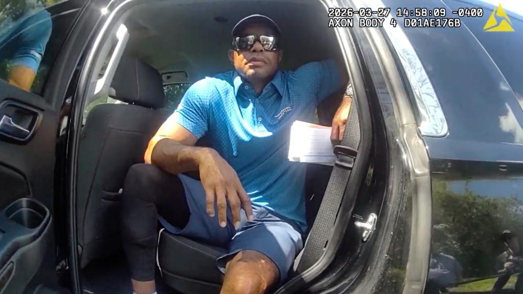 Golfer Tiger Woods sits in an unmarked police vehicle.