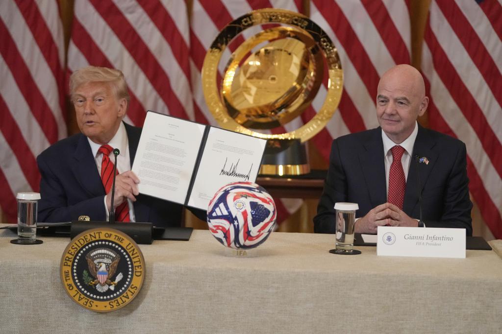 President Donald Trump holds the sign charter for the 2026 FIFA World Cup soccer tournament