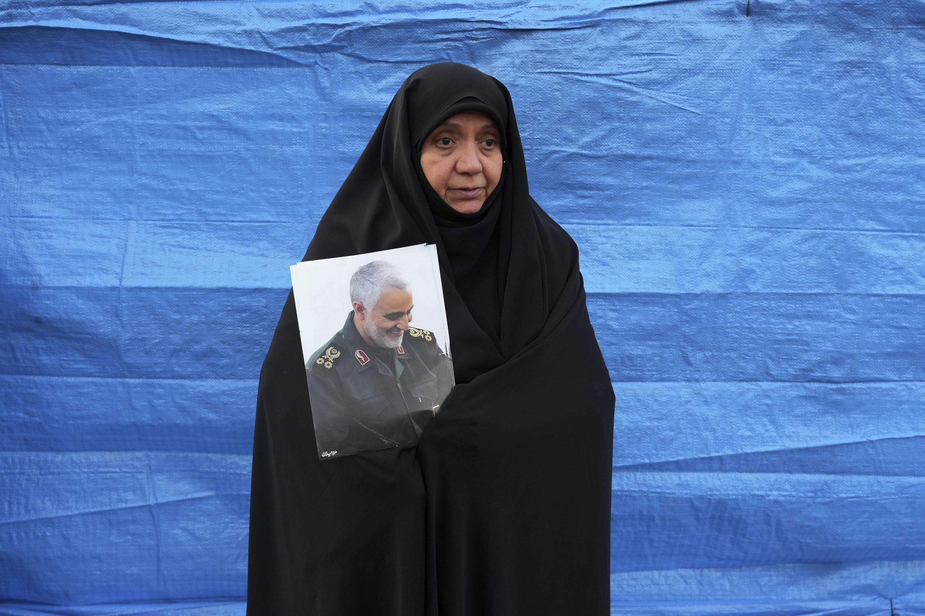 A woman holds a portrait of the late Revolutionary Guard Gen. Qassem Soleimani.