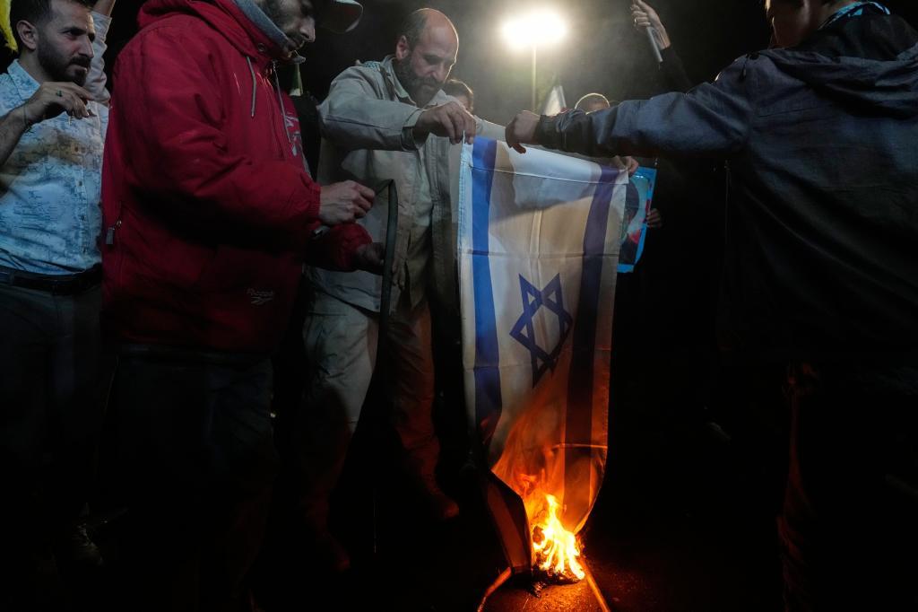 Iranian pro-government demonstrators burn an Israeli flag