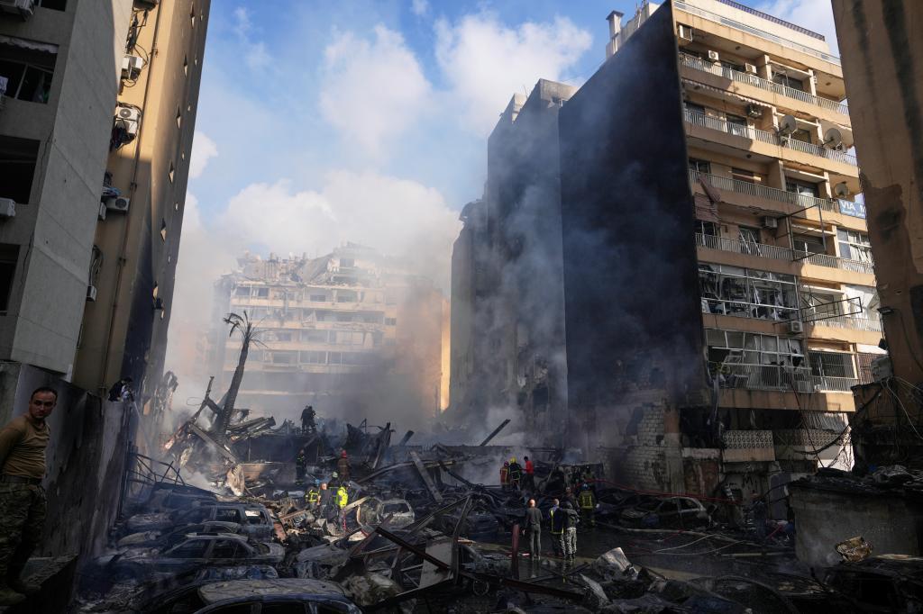 Firefighters, first responders, and volunteers work on smoldering and burning debris
