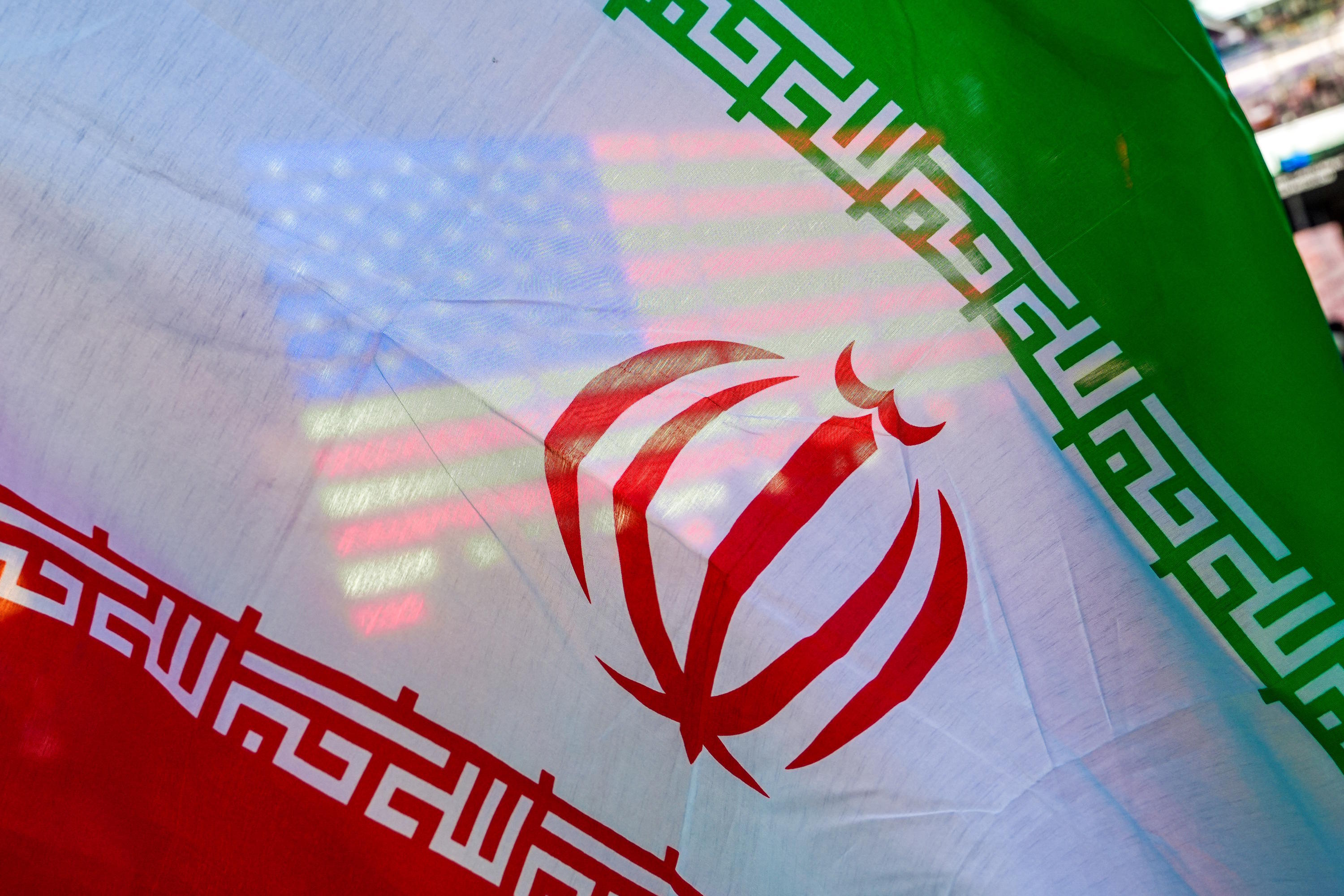 A U.S. flag is seen through the flag of Iran during a protest against the U.S.-Israeli war in Iran.