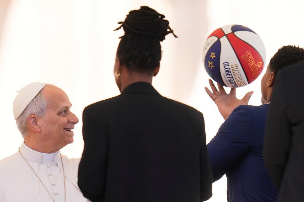 Pope Leo XIV looks at a basketball as he meets athletes from the Harlem Globetrotters
