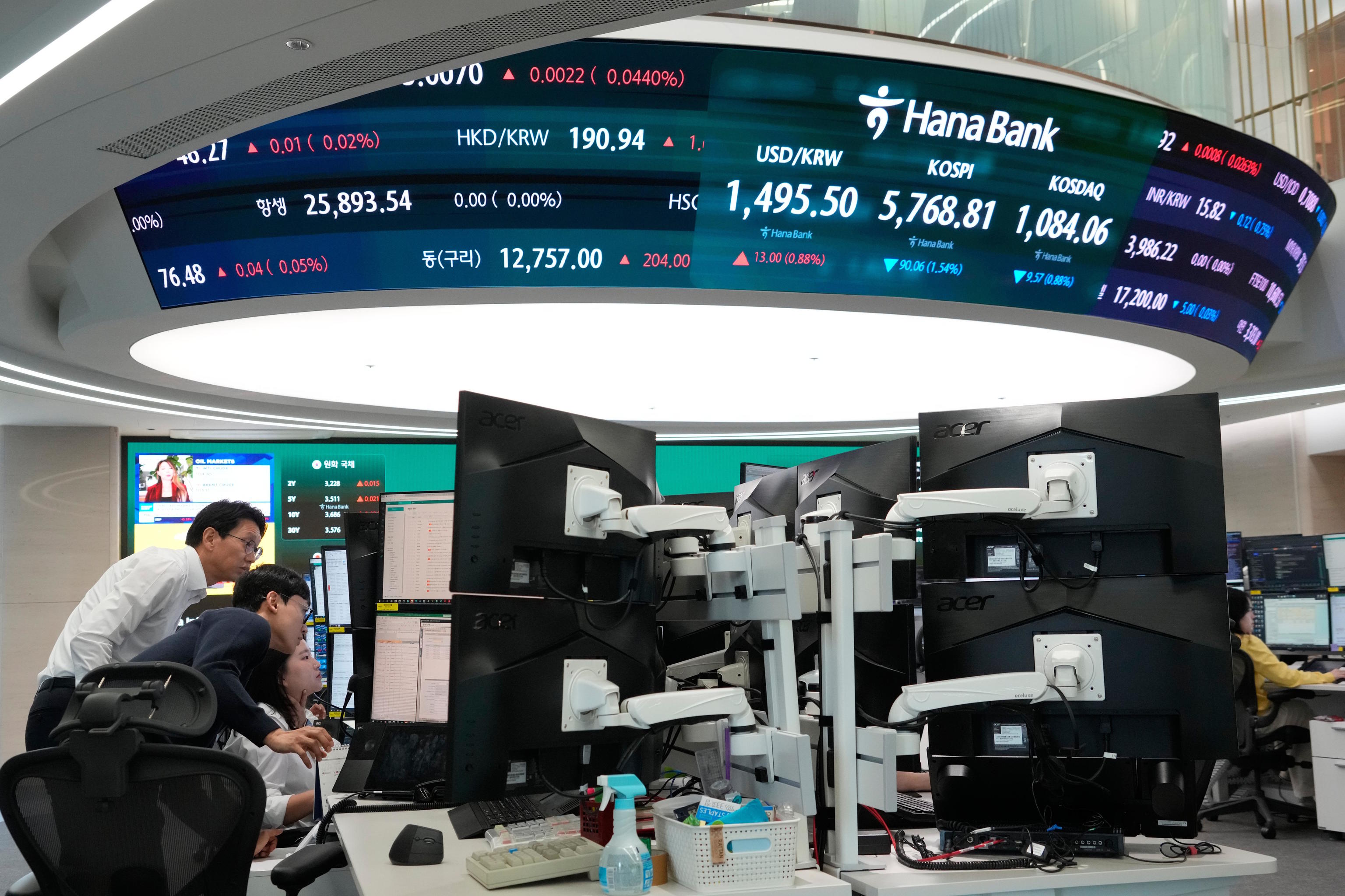 Currency traders watch monitors near a screen showing the Korea Composite Stock Price Index.