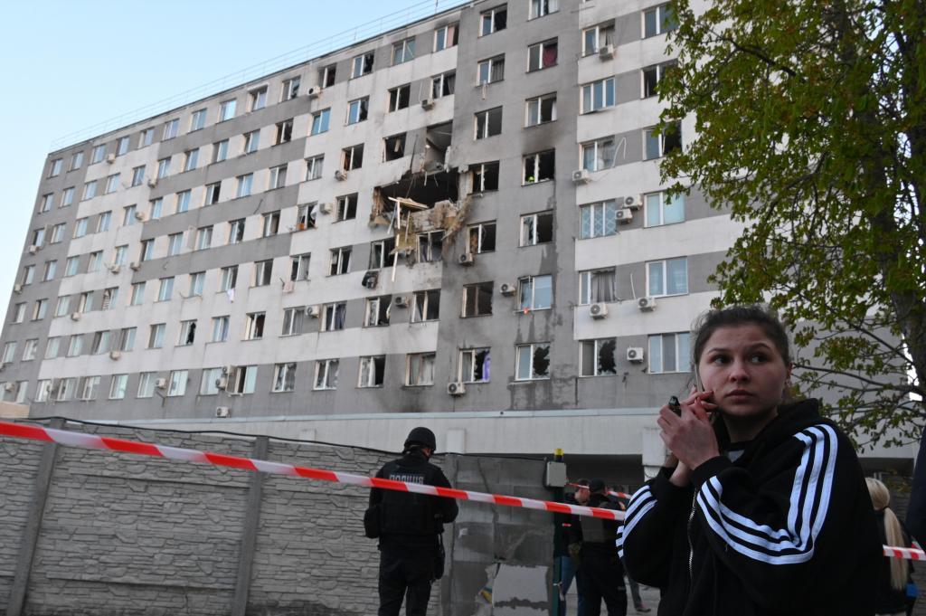 A woman speaks via a phone in front of residential building which was damaged after a Russian drone strike on Odesa