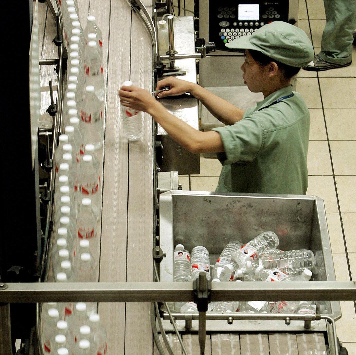 A Chinese worker selects water bottles at the production line.