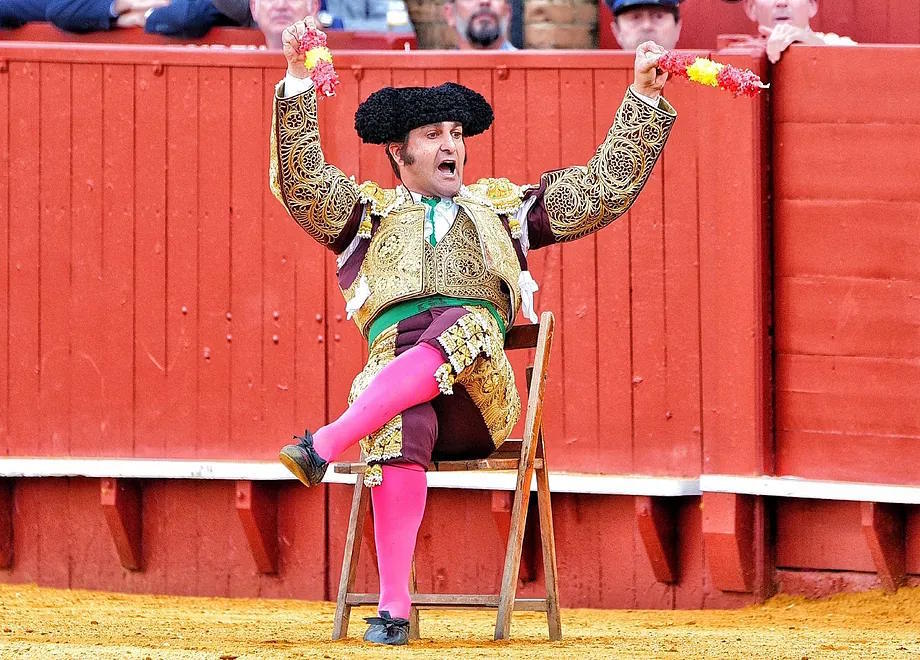 Morante calls the bull while seated in a chair to execute a pass.