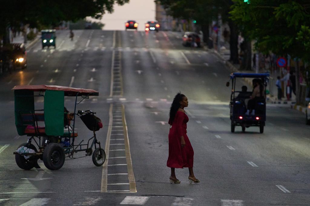 People cross an avenue in Havana.