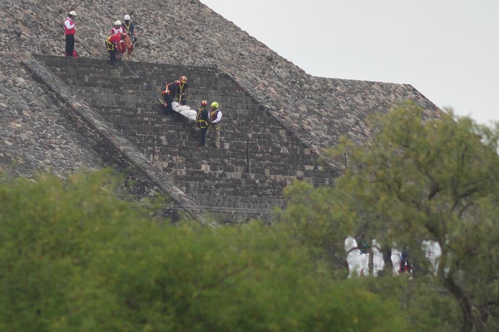 Forensic workers carry the body of a victim down a pyramid after authorities said a gunman opened fire