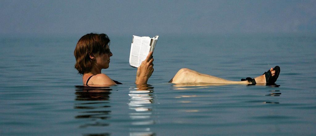 A German tourist reads a tourist guide as she floats in the Dead Sea