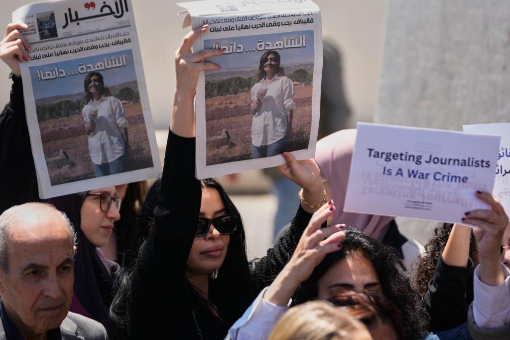 Journalists hold up newspapers showing portraits of Lebanese journalist Amal Khalil who was killed on Wednesday in an Israeli airstrike