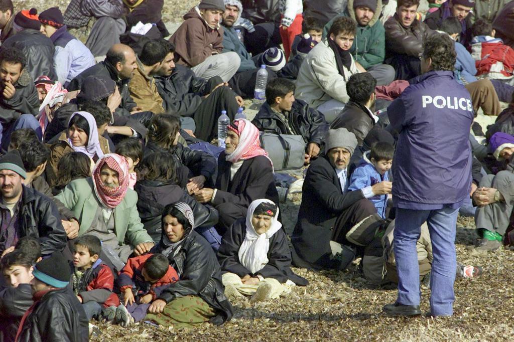 A French police officer watches over a group of immigrants