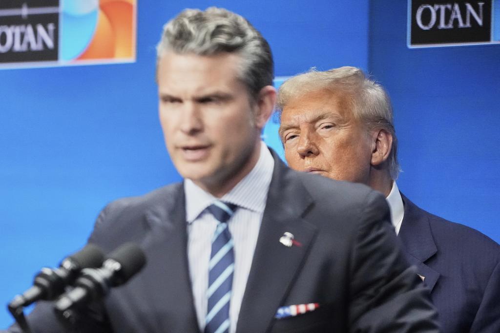 President Donald Trump watches Defense Secretary Pete Hegseth during a press conference