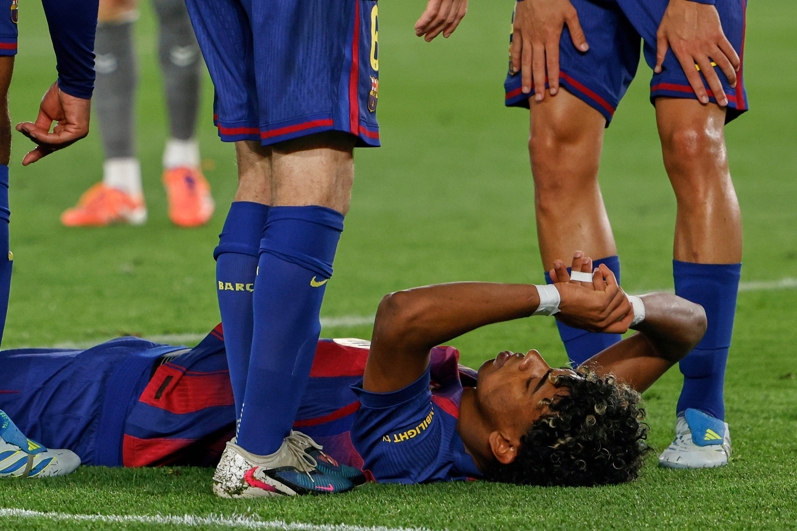 Barcelona's Lamine Yamal lays on the pitch after getting injured.
