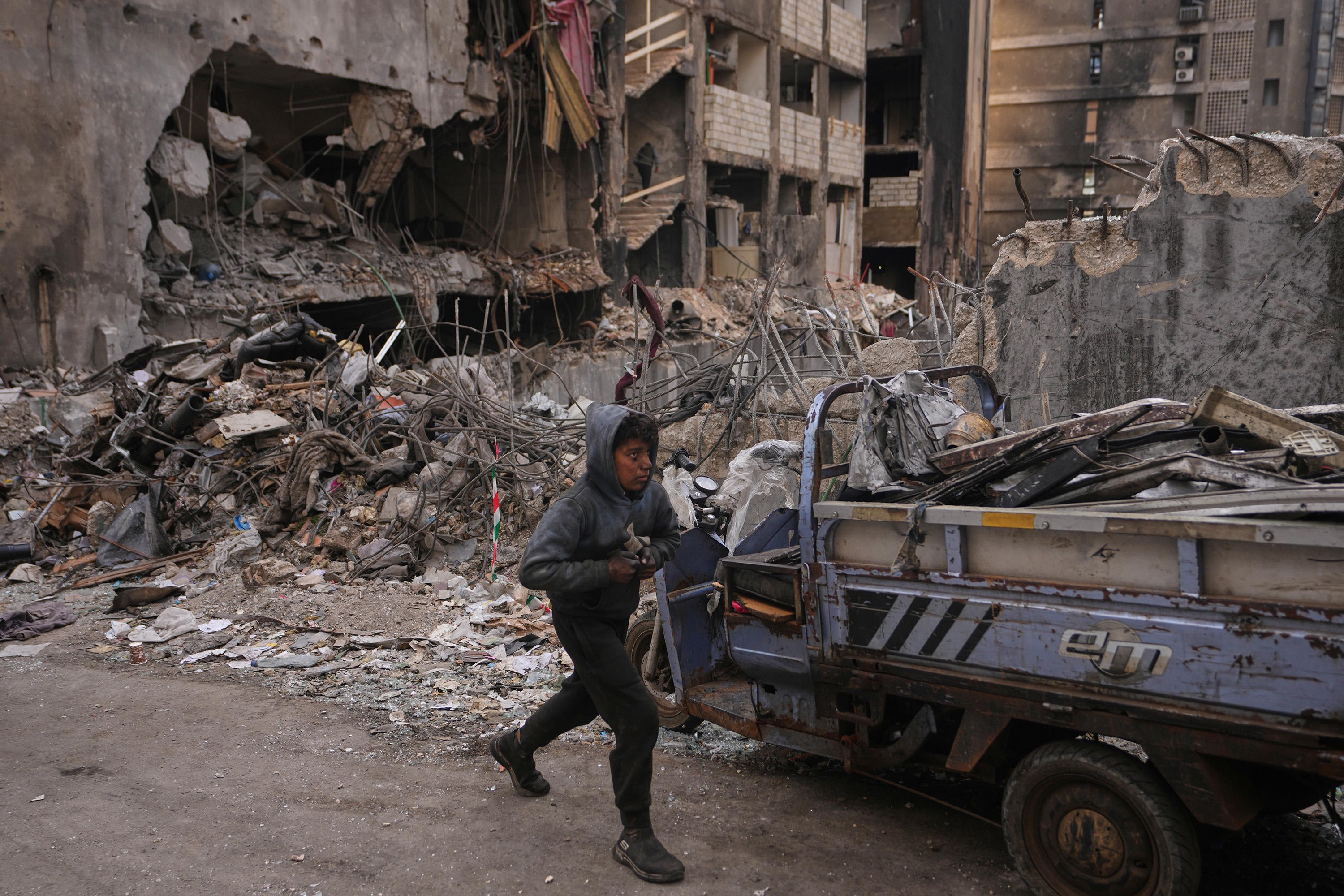 A boy collects scrap metal amid debris at the site of a building destroyed in an Israeli airstrik.