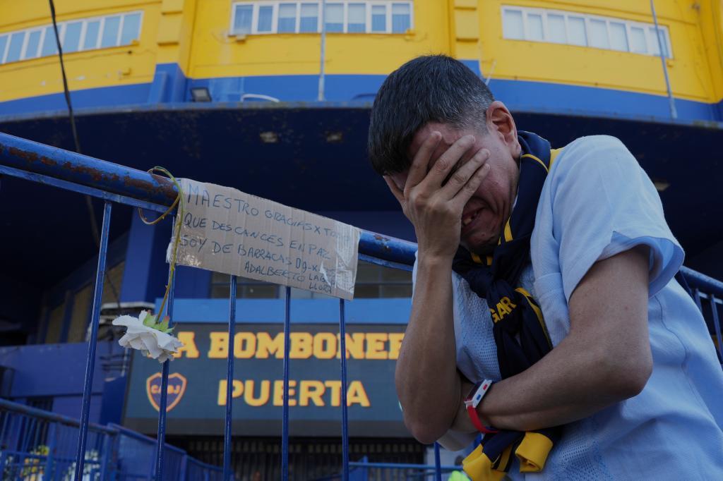 A Boca Juniors fan covers his face outside La Bombonera stadium.
